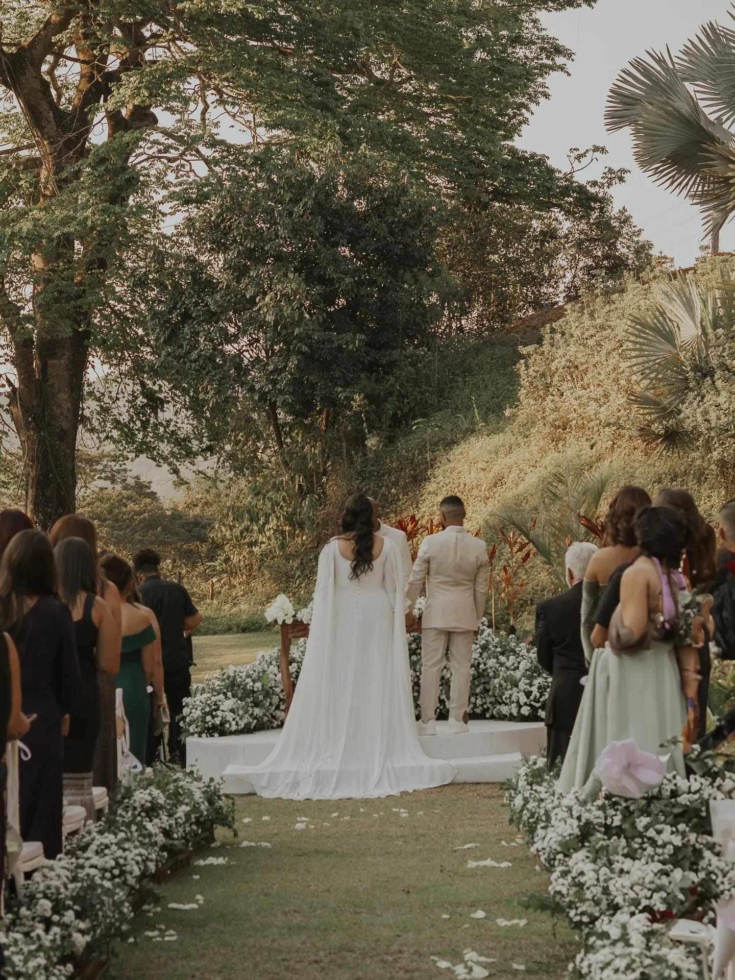 Cerimônia de casamento ao ar livre, noivos no altar entre árvores e flores brancas