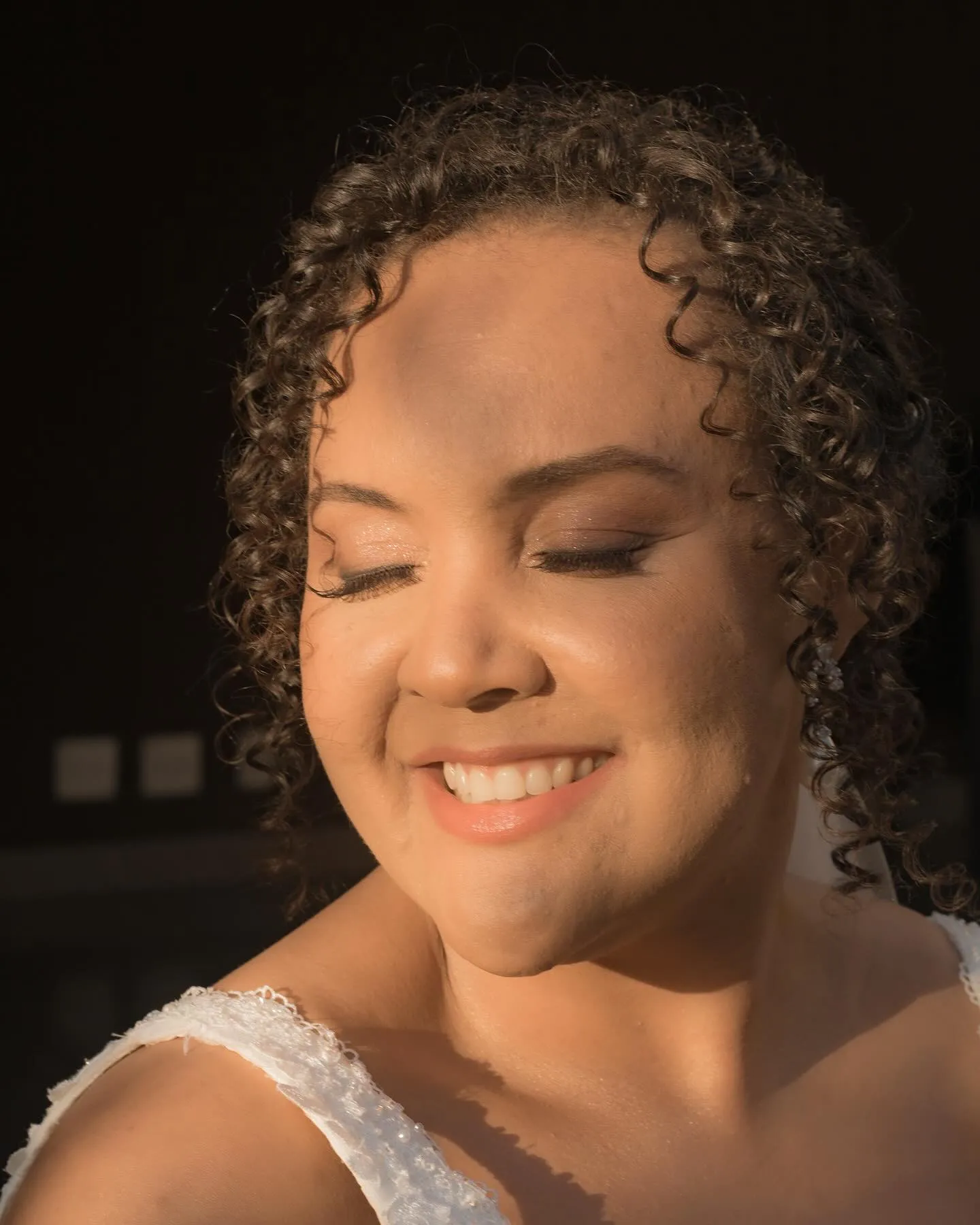 Noiva sorrindo de olhos fechados sob a luz do fim de tarde