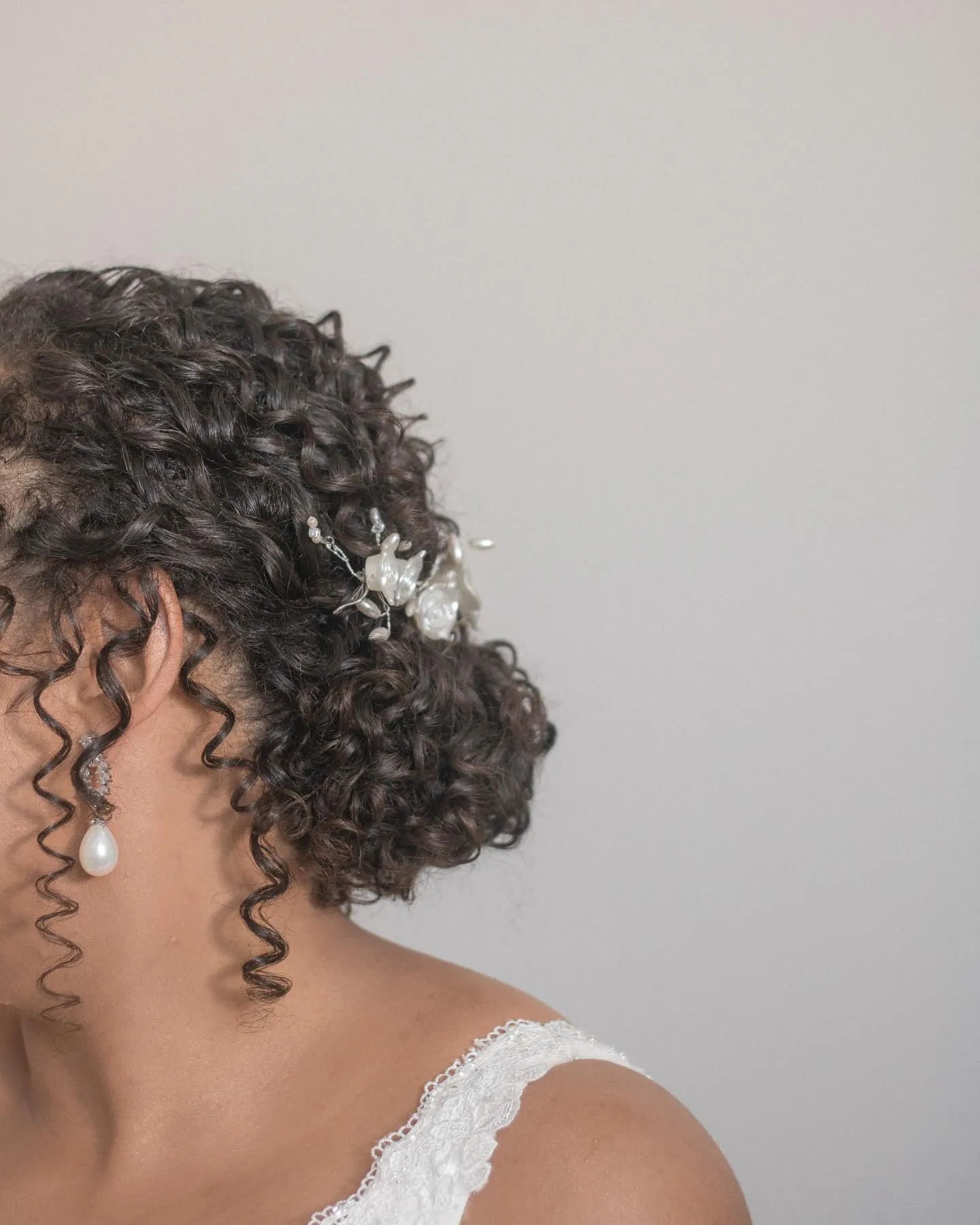Detalhe do penteado cacheado e brinco de pérola da noiva