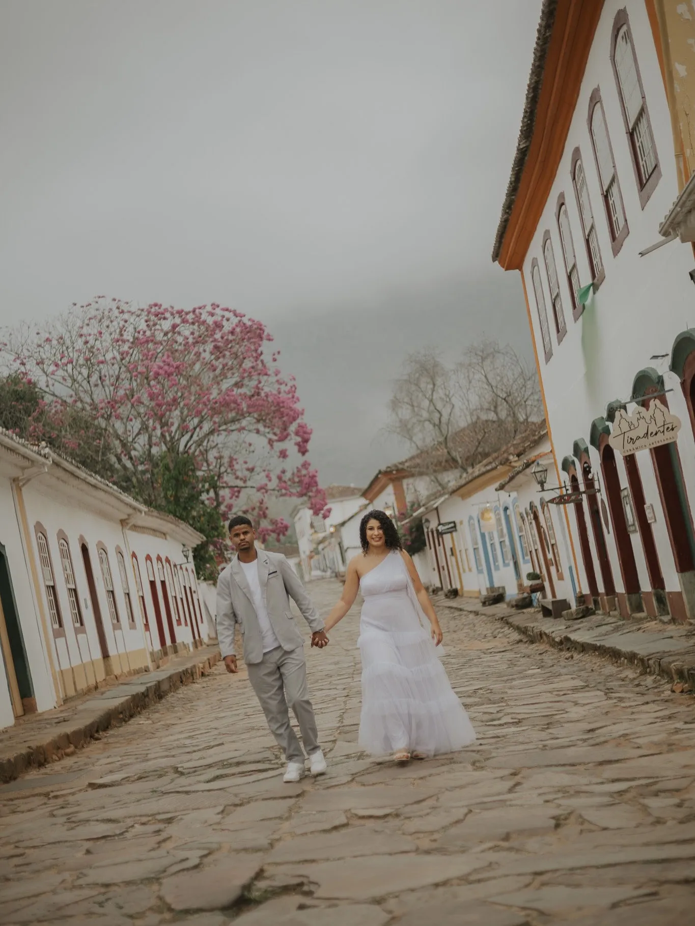 Casal caminhando de mãos dadas em rua histórica de Tiradentes